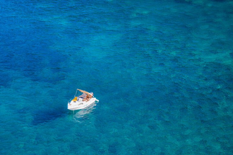 Aerial shot of a white boat floating on clear turquoise waters in Hagenberg, perfect for travel and leisure. Billigreisen Hagenberg